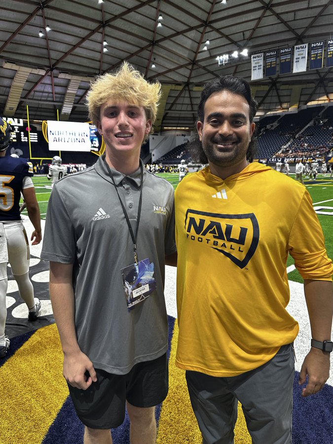 Jax Snyder with a Northern Arizona Lumberjacks football coach on the field at the Walkup Skydome